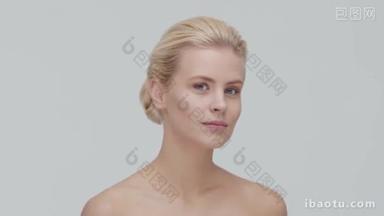 年轻、<strong>美丽</strong>、自然的金发女子应用护肤霜的工作室肖像。 面部整容、化妆品及化妆.